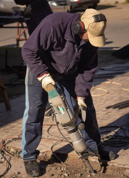 Adam beton kırıcıyla betonu kırıyor.