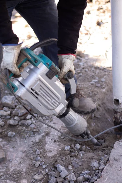 Adam beton kırıcıyla betonu kırıyor.