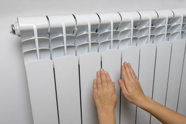 Ellerini ısıtıcının üstüne koy. Ev merkezi ısıtma sistemi. Isıtıcının üstünde sıcak eller