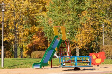 Playground for little kids in the park. An empty children's playground is waiting for children. The early sunny morning.