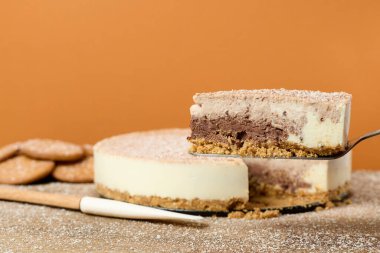 Turuncu zemin üzerinde kurabiyeler olan koyu ve beyaz çikolatalı pasta.