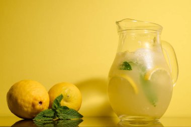 Sarı zemin üzerinde limon ve nane ile taze limonata.