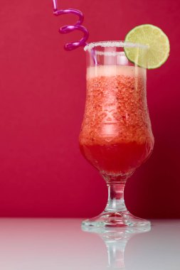 Kırmızı arka planda saman içilen çilek kokteyli.