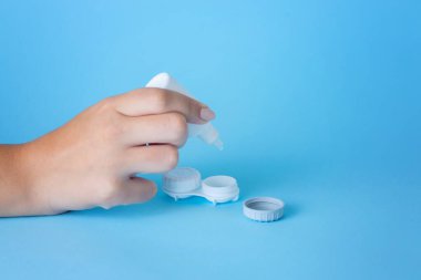 Parmak ve solüsyon şişelerinde yakın plan kontak lens. Lenslere odaklan. Boşluğu kopyala