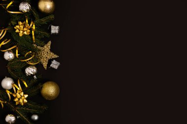 Noel arkaplanı, köknar dalları, altın süslemeler ve siyah bir masanın üzerinde çam kozalakları. Düz yatıyordu. Kopyalama alanı olan üst görünüm