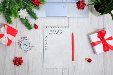Noel kompozisyonu. 2022 için golleri olan bir not. Dizüstü bilgisayar, defter, kalem, hediye kutuları, alarm, toplar ve yıldızlar. İş dünyası Noel 'i. Hedefler ve hedefler