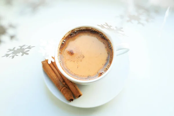 Una taza de café sobre guirnaldas bokeh de Navidad en la casa en la mesa con un suéter en el fondo y decoraciones. Humor de invierno, decoración festiva, Navidad mágica. — Foto de Stock