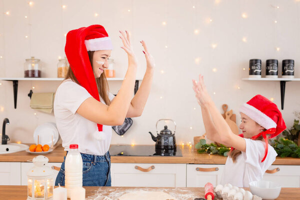 Children prepare Christmas cookies in a cozy kitchen. The sisters prepare a festive meal for the family together. Cute girls bake, play and fool around with flour. The concept of a child chef