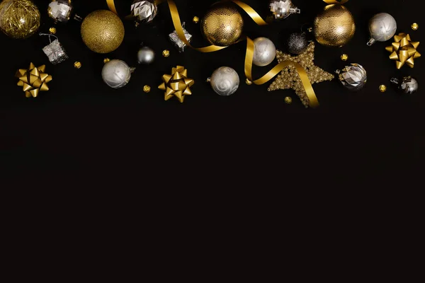 Рождественский фон с еловыми ветвями, золотыми украшениями и сосновыми шишками на черном столе. Плоский лежал. вид сверху с местом для копирования Стоковая Картинка