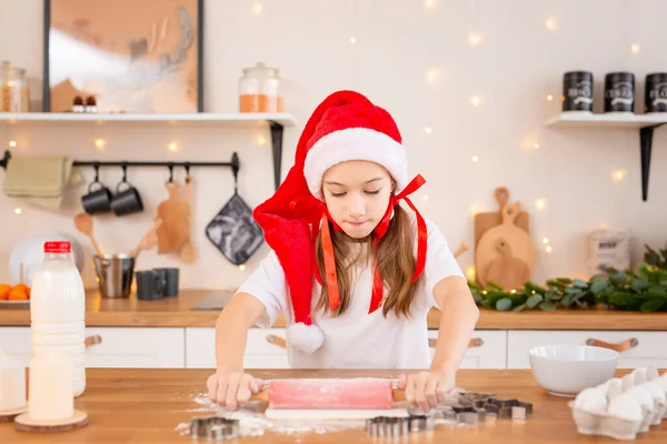 여자 애들은 크리스마스 쿠키를 아늑 한 부엌에서 요리합니다. 자녀들은 가족을 위해 축일 음식을 준비 한다. 귀여운 소녀는 집에서 만든 축제용 비스킷을 굽는다. 인생 스타일의 순간. 산타 조수. 어린이 주방장 개념 — 스톡 사진