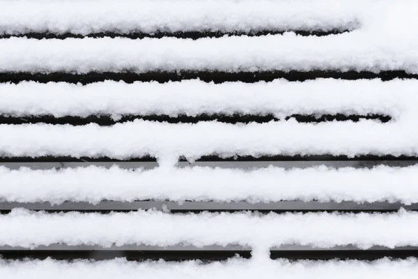 Bankın karla kaplı tahtaları bir ritim, bir düzen oluşturuyor. Kış soyut arkaplanı.