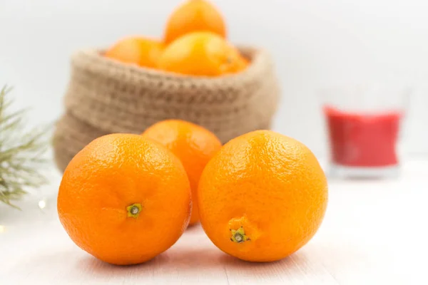 Geurende mandarijnen in een gebreide jutemand op een houten tafel. — Stockfoto