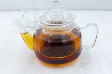 Tahta beyaz bir masada, cam çaydanlıkta demlenmiş siyah çay..