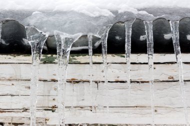 Buz saçakları ahşap bir evin çatısında asılı..