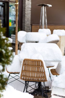 Soğuk kar mevsiminde kar yağışı olan bir sokak kafesinde boş mobilyalar..