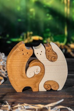 Ormanın arka planında el yapımı bir kedi ailesi şeklinde ahşap yapboz.