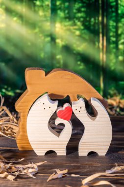 Ormanın arka planında el yapımı bir kedi ailesi şeklinde ahşap yapboz.