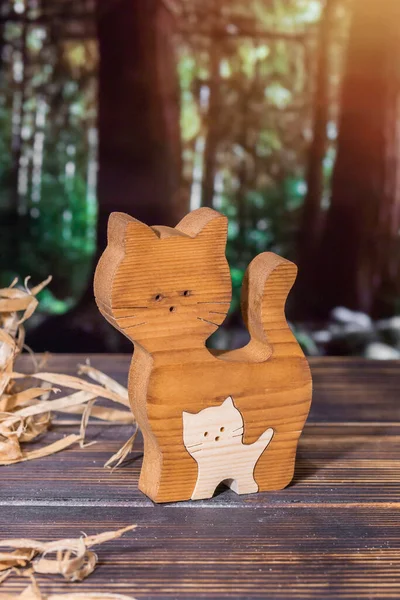 Ormanın arka planında el yapımı bir kedi ailesi şeklinde ahşap yapboz.