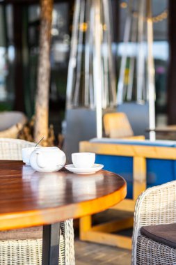 Her iki tarafında yapay rattan mobilyalar olan bir kafenin boş terasında yürü..