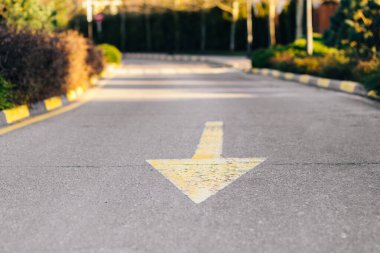 Bulanık bir arkaplanda asfalt bir yolda sarı ok işaretçisi