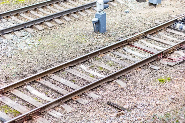 Paslı metal demiryolu rayları ve çakıllar yakın plan.