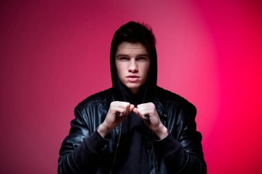 Siyah deri ceketli, sevimli, vahşi adam modeli. Pembe stüdyo geçmişinde yakışıklı bir adamın portresi. Siyah ceketli adam. Pembe arka planda Deri Ceketli Genç Moda Adamı.