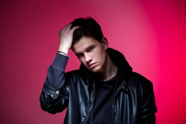 Siyah deri ceketli, sevimli, vahşi adam modeli. Pembe stüdyo geçmişinde yakışıklı bir adamın portresi. Siyah ceketli adam. Pembe arka planda Deri Ceketli Genç Moda Adamı.