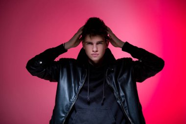 Siyah deri ceketli, sevimli, vahşi adam modeli. Pembe stüdyo geçmişinde yakışıklı bir adamın portresi. Siyah ceketli adam. Pembe arka planda Deri Ceketli Genç Moda Adamı.