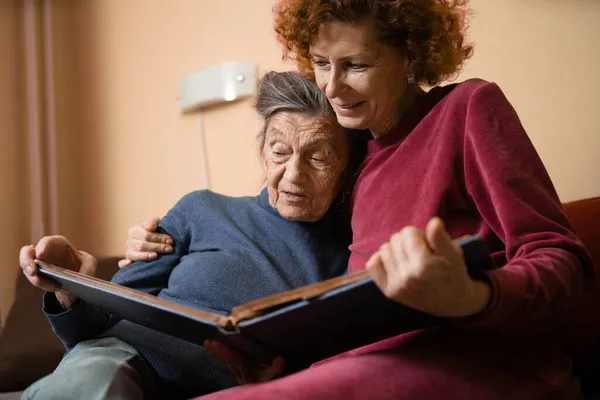 Büyük kadın ve yetişkin kızı oturma odasında birlikte fotoğraf albümü izliyorlar, neşeli bir şekilde anıları tartışıyorlar. Ailelerle hafta sonu, aile günü, şükran günü, annemin tatili..
