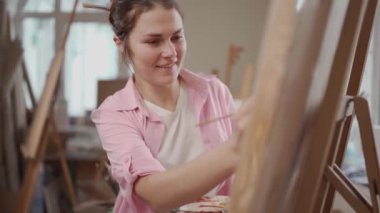 Sanat, yaratıcılık, hobi ve yaratıcı meslek kavramı. Yaratıcılığı canlandırmak. Resim stüdyosunda resim yapan bir kadın. Atölyede resim yapan çekici bir kadın sanatçı. Kadın hobisi, aktivite, meslek