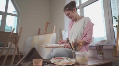 Sanat, yaratıcılık, hobi ve yaratıcı meslek kavramı. Yaratıcılığı canlandırmak. Resim stüdyosunda resim yapan bir kadın. Atölyede resim yapan çekici bir kadın sanatçı. Kadın hobisi, aktivite, meslek