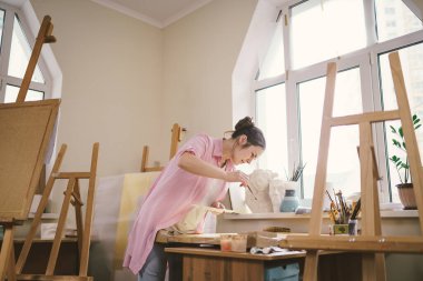 Sanat, yaratıcılık, hobi ve yaratıcı meslek kavramı. Yaratıcılığı canlandırmak. Resim stüdyosunda resim yapan bir kadın. Atölyede resim yapan çekici bir kadın sanatçı. Kadın hobisi, aktivite, meslek.