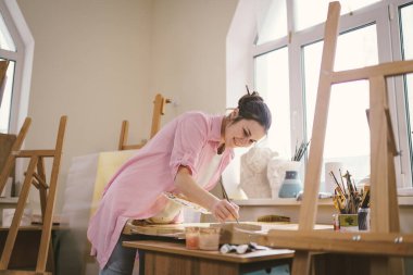 Stüdyoda çalışan kadın sanatçı. Yaratıcı çalışma alanı, resim dersi, tuval sehpası, sanat terapisi. İlham, yaratıcılık, yetenek, zanaat konsepti. Artist stüdyosu. İnsanlar, eğlence ve hobi.