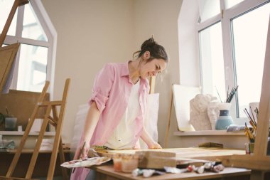 Sanat, yaratıcılık, hobi ve yaratıcı meslek kavramı. Yaratıcılığı canlandırmak. Resim stüdyosunda resim yapan bir kadın. Atölyede resim yapan çekici bir kadın sanatçı. Kadın hobisi, aktivite, meslek.