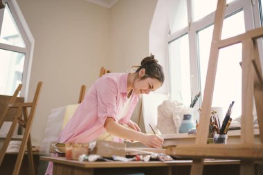 Stüdyoda çalışan kadın sanatçı. Yaratıcı çalışma alanı, resim dersi, tuval sehpası, sanat terapisi. İlham, yaratıcılık, yetenek, zanaat konsepti. Artist stüdyosu. İnsanlar, eğlence ve hobi.