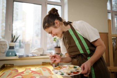 Sanat, yaratıcılık, hobi ve yaratıcı meslek kavramı. Yaratıcılığı canlandırmak. Resim stüdyosunda resim yapan bir kadın. Atölyede resim yapan çekici bir kadın sanatçı. Kadın hobisi, aktivite, meslek.