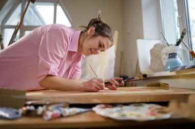 Sanat, yaratıcılık, hobi ve yaratıcı meslek kavramı. Yaratıcılığı canlandırmak. Resim stüdyosunda resim yapan bir kadın. Atölyede resim yapan çekici bir kadın sanatçı. Kadın hobisi, aktivite, meslek.