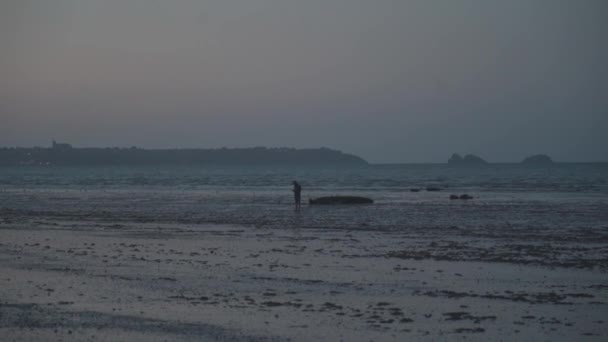 Tema Ocean ebb en el norte de Francia en la región de Bretaña. Hombre turista camina a lo largo de la costa al atardecer. Costa Atlántica. Playa del Océano Atlántico durante marea baja, con dunas de arena. Puesta de sol atmosférica y calmante — Vídeo de stock