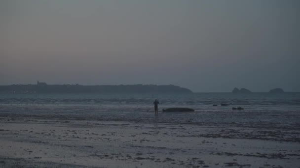 Людина - турист ходить уздовж узбережжя після низького припливу на заході сонця в північній частині Френсіса в районі крихти. Ебб на узбережжі Бретані. Сценічний піщаний пляж і рефлюенс — стокове відео