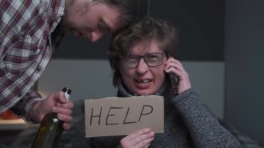 Yüzü yaralanmış korkmuş bir kadın yardım istiyor. Alkolik agresif adam yaralı, korkmuş, çaresiz, korkmuş, dövülmüş kadını istismar ediyor. Korku içinde yaşayan kadın polisi arıyor ve elinde kelimelerle işaret tutuyor.