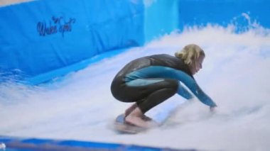 Su sporu aktivitesi, denge konsepti. Küçük sporcu ev içinde sörf yapmaktan hoşlanıyor. Gençler spor kompleksinde simülatörde dalgalarda sörf yapıyor. Sörf koçu ve öğrenci dalga simülatöründe toplandı