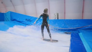 Flow Rider 'da çocuk ve eğitmen. Kapalı alanda sörf eğitimi almış. Su sörfü eğitimi alan bir genç. İçeride dalga simülatörü eğitimi alıyor. Genç sörfçü, üretilmiş dalgalar üzerine eğitim alırken. Su sporları