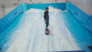 Çocuklar için kapalı sörf kulübü. Tema aktif eğlence ve su üzerinde ekstrem spor. Öğrenci ve koç dalga simülatöründe sörf eğitimi alıyor. Su parkında sörf tahtası.