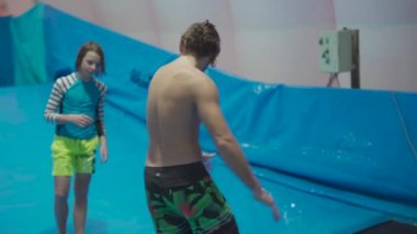 Çocuklar için kapalı sörf kulübü. Tema aktif eğlence ve su üzerinde ekstrem spor. Öğrenci ve koç dalga simülatöründe sörf eğitimi alıyor. Su parkında sörf tahtası.