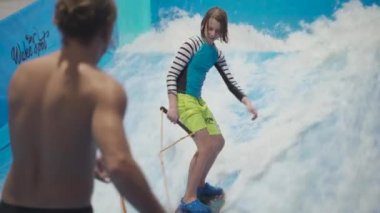 Çocuklar için kapalı sörf kulübü. Tema aktif eğlence ve su üzerinde ekstrem spor. Öğrenci ve koç dalga simülatöründe sörf eğitimi alıyor. Su parkında sörf tahtası.