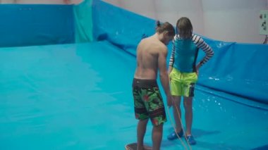 Su sporu aktivitesi, denge konsepti. Küçük sporcu ev içinde sörf yapmaktan hoşlanıyor. Gençler spor kompleksinde simülatörde dalgalarda sörf yapıyor. Sörf koçu ve öğrenci dalga simülatöründe toplandı