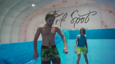 Flow Rider 'da çocuk ve eğitmen. Kapalı alanda sörf eğitimi almış. Su sörfü eğitimi alan bir genç. İçeride dalga simülatörü eğitimi alıyor. Genç sörfçü, üretilmiş dalgalar üzerine eğitim alırken. Su sporları