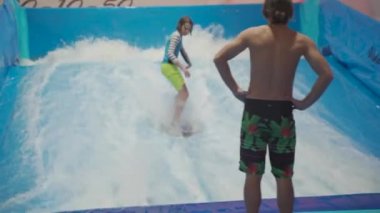 Flow Rider 'da çocuk ve eğitmen. Kapalı alanda sörf eğitimi almış. Su sörfü eğitimi alan bir genç. İçeride dalga simülatörü eğitimi alıyor. Genç sörfçü, üretilmiş dalgalar üzerine eğitim alırken. Su sporları
