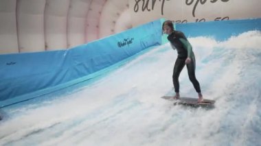Çocuklar için kapalı sörf kulübü. Tema aktif eğlence ve su üzerinde ekstrem spor. Öğrenci ve koç dalga simülatöründe sörf eğitimi alıyor. Su parkında sörf tahtası.