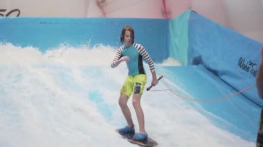 Flow Rider 'da çocuk ve eğitmen. Kapalı alanda sörf eğitimi almış. Su sörfü eğitimi alan bir genç. İçeride dalga simülatörü eğitimi alıyor. Genç sörfçü, üretilmiş dalgalar üzerine eğitim alırken. Su sporları
